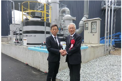 発電設備の前で握手する岡田吉充トーホーグループ社長㊧と広瀬栄・養父市長㊨
