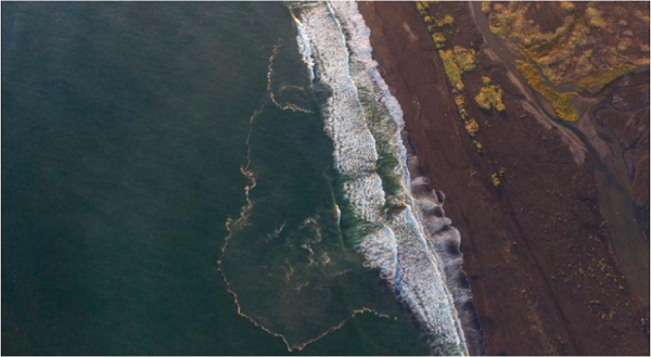 ドローンで上空から撮影した海岸線漂う白灰色の油膜の帯