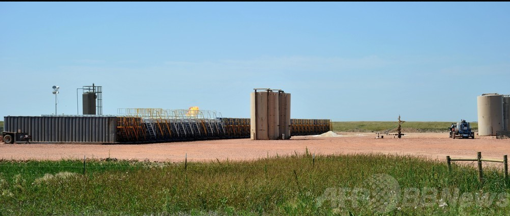 米ノースダコダ州のタイオガでのシェールガス開発状況。フラッキング用貯水タンクとその向こうに発掘したガスの燃えるフレアが見える
