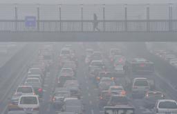 有害物質含んだ濃霧のため、日中でも見通しが悪い北京市内の道路＝２９日