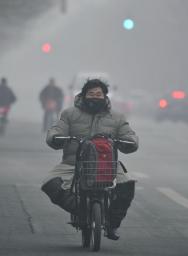 有害物質を含んだ濃霧の中、マスクを着け自転車に乗る男性＝１月、北京