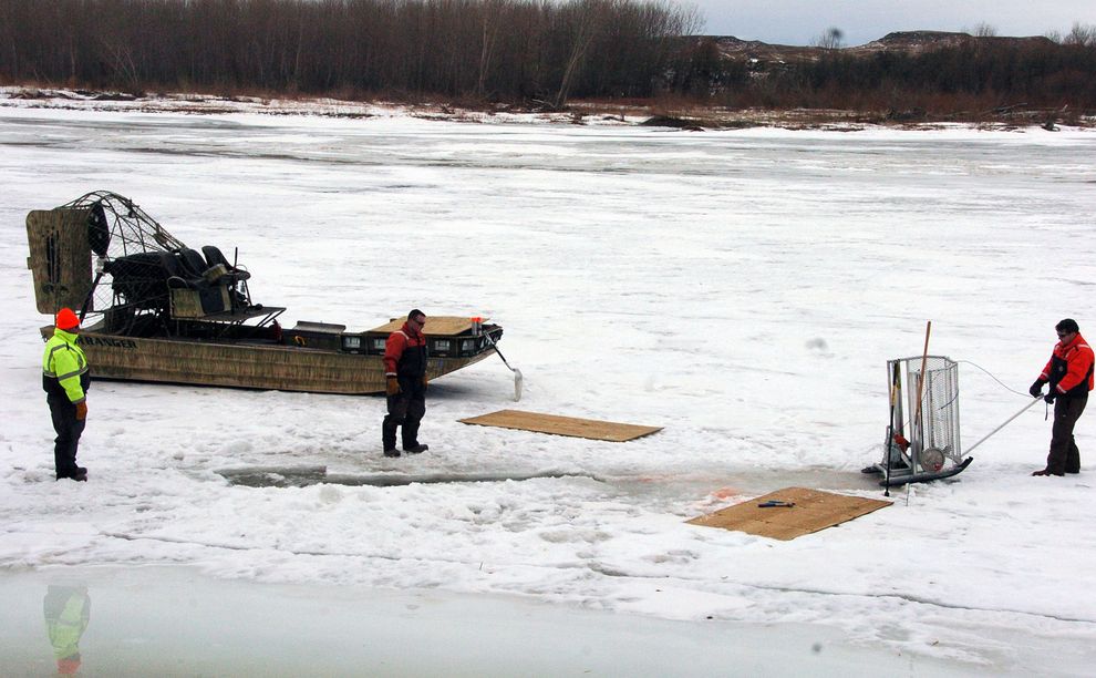 19日、モンタナ州クレーンに近いイエローストーン川で、氷に穴をあけて清掃にあたる作業員たち。17日に、パイプラインから19万リットルの原油が流出した。（Photograph by Matthew Brown, Associated Press）
