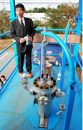 焼却飛灰から放射性セシウムを除去する実証試験装置を説明する内田教授