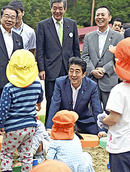 砂場で遊ぶ園児たちを笑顔で見詰める安倍首相＝１７日午前１１時ごろ、川内村のかわうち保育園