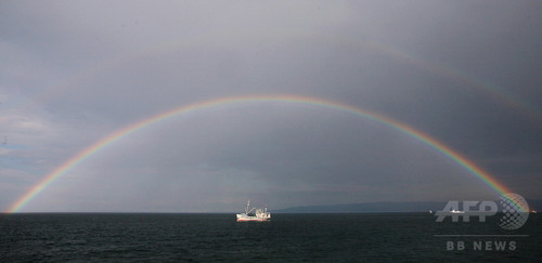 虹がかかったバイカル湖の湖上を移動する船