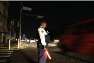 停電で信号が消えた交差点で交通整理をする警察官＝２７日午後９時４７分、東京都八王子市大和田町