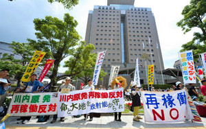 鹿児島県庁（後方）の前で九電川内原発の再稼働反対を訴える人たち＝１３日、鹿児島市で