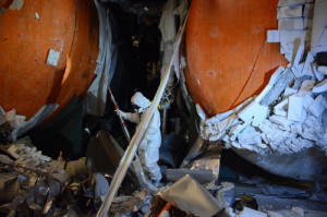 東京電力福島第１原発１号機で、オレンジ色をした非常用復水器（ＩＣ）のタンク部分を調べる原子力規制庁職員。保温材のようなものがはがれている＝２０１３年５月３１日、原子力規制委員会提供