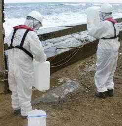 新たな汚染水漏れが見つかった東京電力福島第１原発の排水溝出口付近で、海水を採取する福島県の職員＝３日午後（同県提供）