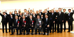 力強く拳を突き上げる佐藤知事（前列中央）や東社長（同右から２人目）ら