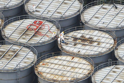 汚染水が漏えいした福島第１原発の貯蔵タンク（中央右）の上で作業をする人たち＝福島県大熊町で