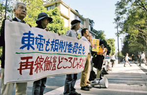 横断幕を掲げて東京電力の再稼働申請を批判する反対派の人たち＝２７日午前、東京・六本木の原子力規制委員会前で