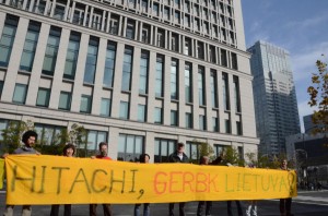 「日立はリトアニアを尊重せよ」。リトアニア語で書かれた横断幕を広げる参加者たち。後ろが日立本社ビル。=写真：田中撮影=
