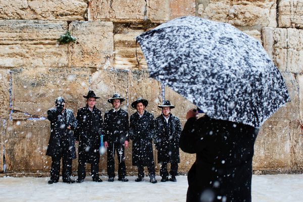 エルサレムに降りしきる雪の中、観光客が嘆きの壁の前で記念撮影。