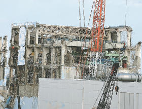 ２０１１年３月１５日、３号機から流入した水素ガスによって爆発したとみられている福島第１原発４号機。事故当時は定期検査中で、核燃料は建屋内の燃料プールに移されていた。プールの天井クレーンの上などで、作業が続けられている（代表撮影）