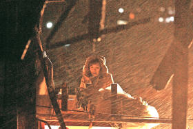 雪が吹き付ける中、防災対策庁舎で祈る三浦ひろみさん。夫の帰りを待ち、通い続けて１年がたつ＝宮城県南三陸町志津川