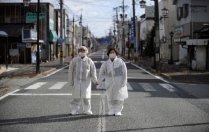 epa03611830 (01/27) Wearing white protective masks and suits, Yuzo Mihara (L) and his wife Yuko pose for photographs on a deserted street in the town of Namie, Fukushima prefecture, Japan, 22 February 2013, in the Fukushima nuclear disaster exclusion zone. Following the 11 March 2011 earthquake, tsunami and nuclear disaster, tens of thousands of people lost their homes and are still living in temporary homes. Like over 100,000 people that are now 'nuclear refugees', the 21,000 residents of Namie had to abandon their homes after the town was evacuated following the nuclear alert. Even if most of former Namie residents still hope to go back to their homes in the future, they are only allowed to return home for a few hours to minimize radiation exposure, and clean their houses.  EPA/FRANCK ROBICHON PLEASE SEE ADVISORY NOTICE epa03611828 FOR FULL FEATURE TEXT