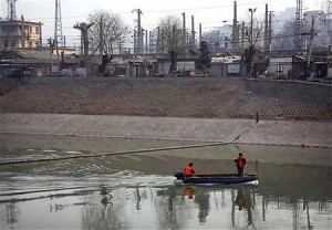 汚染された運河でくず拾いをする人たち（２０１２年３月１６日、中国北京）