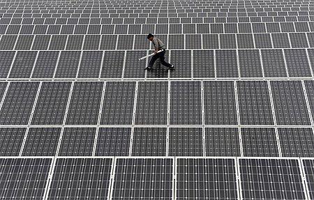 太陽光パネルの上を歩く作業員（２０１２年５月１８日、中国新疆ウイグル自治区アクス）