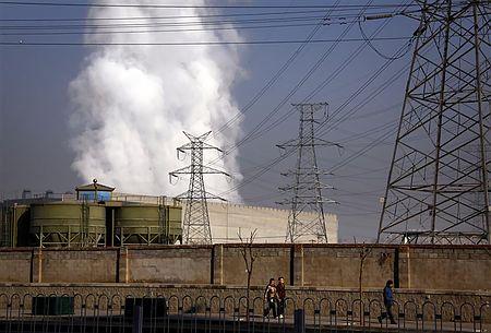 石炭火力発電所の煙突の前を歩く人々（１２年１月１２日、中国北京）