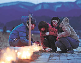 ろうそくの火を見つめる佐々木さん（右）