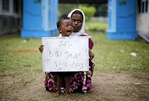 A Rohingya migrant mother (R) and her child, who recently arrived in Indonesia by boat, hold a placard while posing for photographs for immigration identification purposes inside a temporary compound for refugees in Aceh Timur regency, Indonesia's Aceh Province May 22, 2015.  Myanmar's military commander-in-chief said some "boat people" landing in Malaysia and Indonesia this month are likely pretending to be Rohingya Muslims to receive U.N. aid and that many had fled neighbouring Bangladesh, state media reported on Friday.
REUTERS/Beawiharta - RTX1E2GB